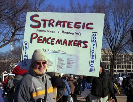 Man with sign that says, 'Strategic Peacemakers'