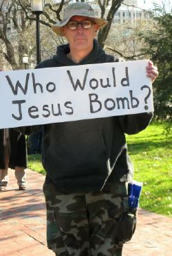 Man in camouflage uniform holds sign that asks: 'Who Would Jesus Bomb?'