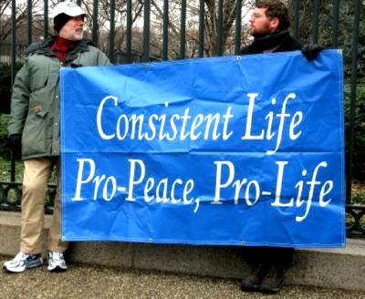 Two men hold white-on-blue 'Consistent Life' banner