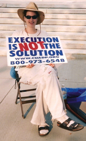 Young woman holds sign that proclaims, 'Execution is NOT the Solution'
