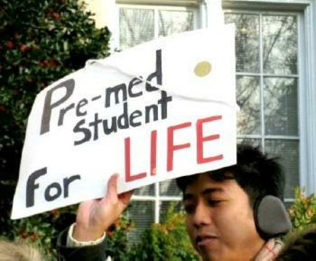 Young man holds sign that says, 'Pre-med Student for Life