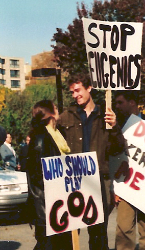 Young couple with signs: 'Stop Eugenics' and 'Who Should Play God'