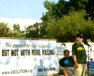 Activists with banner that says, 'We Remember the Victims...BUT NOT WITH MORE KILLING'
